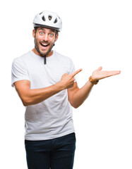 Young handsome man wearing cyclist safety helmet over isolated background amazed and smiling to the...