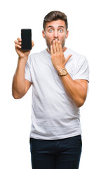 Young handsome man showing smartphone screen over isolated background cover mouth with hand shocked with shame for mistake, expression of fear, scared in silence, secret concept