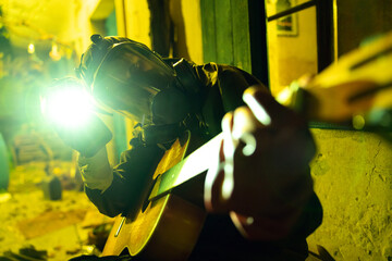 Person in ISO 900 Gas Mask and Full Bio Hazard Body Protective Suite Playing an Acoustic Guitar in Probably Toxic Green Yellow Light Ambience - After Apocalypse Concept