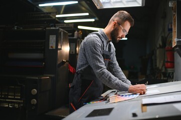 Graphic engineer or worker checking imprint quality in modern print shop