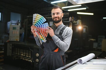 Graphic engineer or worker checking imprint quality in modern print shop