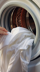 Closeup of a woman's hand putting clothes into the washing machine