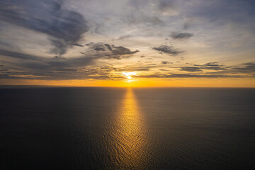 Bright sunrise with yellow sun above the sea surface.