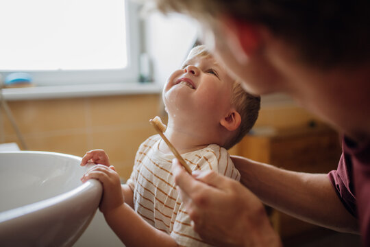 Father brushing little baby boy's teeth in the morning. Morning dental hygiene for toddlers.
