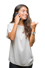 Young beautiful arab woman talking on the phone over isolated background pointing and showing with thumb up to the side with happy face smiling