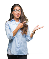 Young beautiful arab woman wearing glasses over isolated background amazed and smiling to the camera while presenting with hand and pointing with finger.