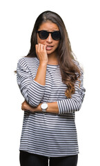 Naklejka premium Young beautiful arab woman wearing sunglasses over isolated background looking stressed and nervous with hands on mouth biting nails. Anxiety problem.