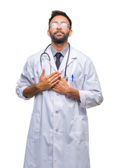 Adult hispanic doctor man over isolated background smiling with hands on chest with closed eyes and grateful gesture on face. Health concept.