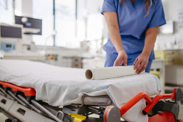 Nurse preparing examination table in emergency room, examination room. Discarding of used paper and...