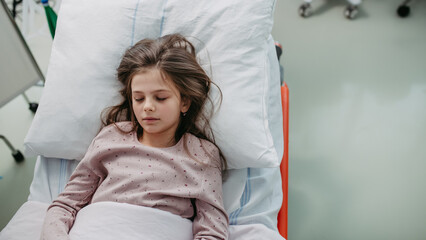 Little girl patient lying in hospital bed. Children in intensive care unit in hospital sleeping.