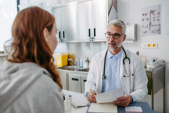 Doctor discussing test results with teenage girl, explaining diagnosis and medication usage. Concept of preventive health care for adolescents.