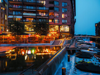 new city residential buildings and restaurants on water in dock and moored watercrafts near,...