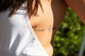 De cerca chica mostrando tatuaje con mensaje vivir libre