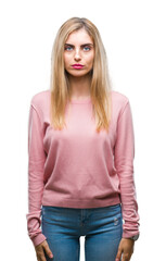 Fototapeta premium Young beautiful blonde woman wearing pink winter sweater over isolated background with serious expression on face. Simple and natural looking at the camera.