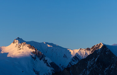 vue panoramique sur les sommets enneigés éclairés par les derniers rayons du soleil couchant