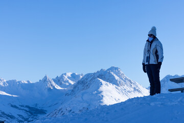 Naklejka na ściany i meble vue panoramique d'une femme qui admire le paysage de montagne hivernal debout sur un sommet enneigé.