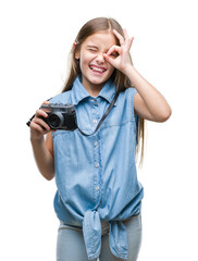 Young beautiful girl taking photos using vintage camera over isolated background with happy face smiling doing ok sign with hand on eye looking through fingers