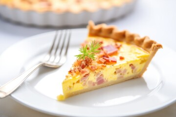 freshly baked quiche lorraine on a white plate with a fork