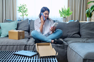 Young woman unpacking online purchase box with new smartphone