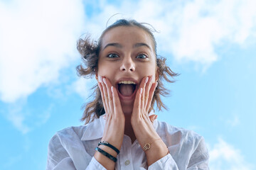 Close up face of emotional laughing female teenager looking down at camera