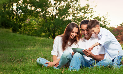 Portrait of an intarnational family playing tablet PC in in the park