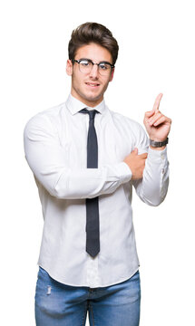 Young business man wearing glasses over isolated background with a big smile on face, pointing with hand and finger to the side looking at the camera.