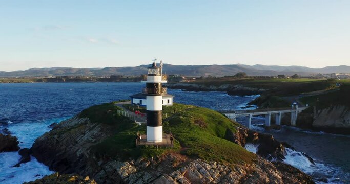 Drone video of lonely lighthouse in sunset on the coast of Galicia, Spain. Island of Pancha (Isla Pancha) clote to Ribadeo village