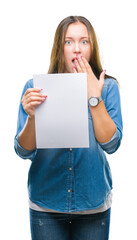 Young caucasian woman holding blank paper sheet over isolated background cover mouth with hand shocked with shame for mistake, expression of fear, scared in silence, secret concept