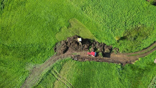 Excavator At Work Digging Soil On Lush Field In Summer 