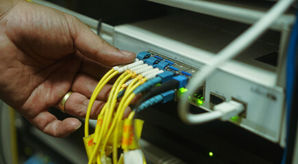 man connects Internet cable in the router.selective focus - obrazy, fototapety, plakaty