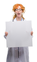 Young redhead doctor woman holding banner scared in shock with a surprise face, afraid and excited with fear expression