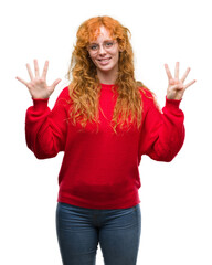 Young redhead woman wearing red sweater showing and pointing up with fingers number nine while smiling confident and happy.