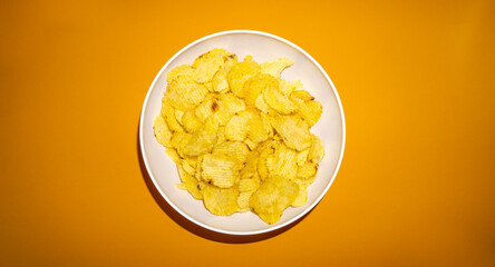 Close-up of potato chips or crisps in bowl against yellow background