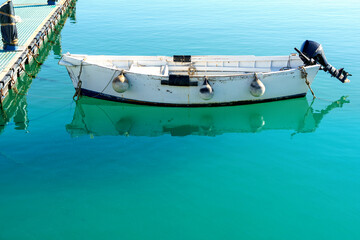 single row boat with motor moored at a jetty