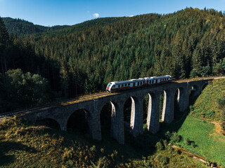 Aerial view of train on historical stone railway bridge in Slovakia. High, fully preserved stone...