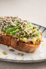 Avocado toast close-up for breakfast or lunch with whole grain bread and assorted seeds. Holistic nutrition concept