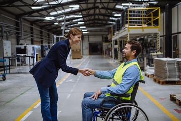 Fototapeta na wymiar Portrait of man in wheelchair working in warehouse, shaking hand with HR manager, director. Concept of workers with disabilities, accessible workplace for employees with mobility impairment.