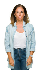 Middle age adult woman wearing casual denim shirt over isolated background with serious expression on face. Simple and natural looking at the camera.