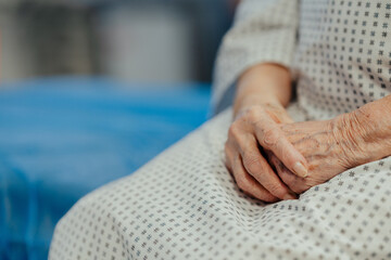 Close up of hands of senior patient on examination table in the hospital. Concept of fear and...