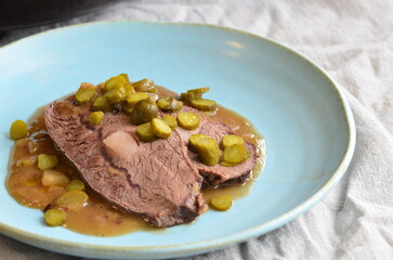 beef stew with pickled green cucumber and serving on a blue plate, czech food