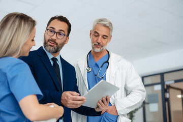 Pharmaceutical sales representative talking with doctors in medical building, presenting them new...