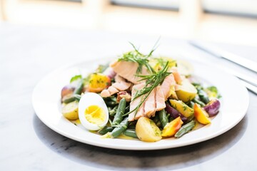brightly lit nicoise salad with gleaming olive oil dressing drizzle