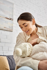 good looking caring jolly mother in cozy homewear breastfeeding her newborn child, modern parenting