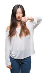 Young asian woman over isolated background looking unhappy and angry showing rejection and negative with thumbs down gesture. Bad expression.