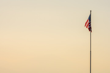 Le drapeau américain flotte mollement devant un ciel hivernal au crépuscule. Symbole d'un empire en déclin ? - obrazy, fototapety, plakaty