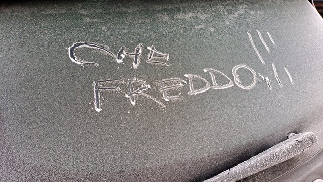 Che freddo ! scritta italiano sul lunotto posteriore di un'auto coperta da ghiaccio.