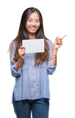 Young asian woman holding blank card over isolated background very happy pointing with hand and finger to the side