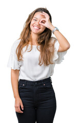 Young beautiful brunette business woman over isolated background doing ok gesture with hand smiling, eye looking through fingers with happy face.