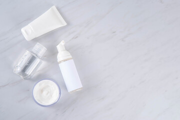 Skinimalism, skin minimalism skin care routine with washing gel, sun protection spf cream, serum bottles and jars on minimal white bathroom background copy space
