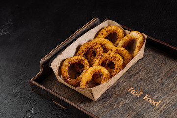 Delicious fast food fried onion rings in a cardboard box for takeaway